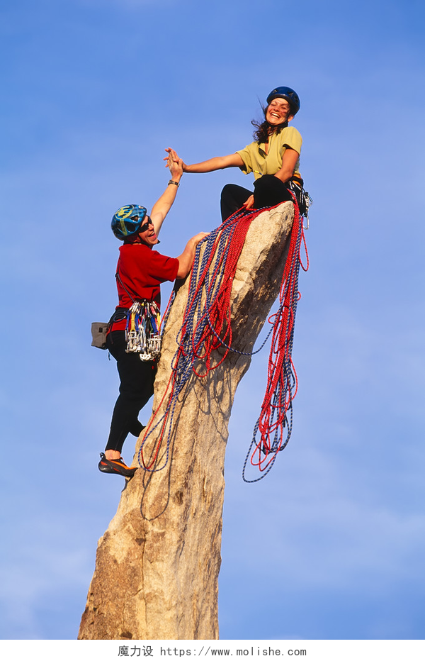 两个人成功登上一个木头树桩顶上攀岩团队达成首脑会议.